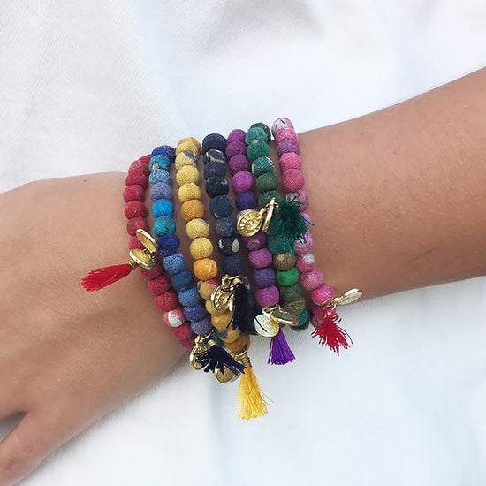 A stack of seven colorful bracelets on wrist