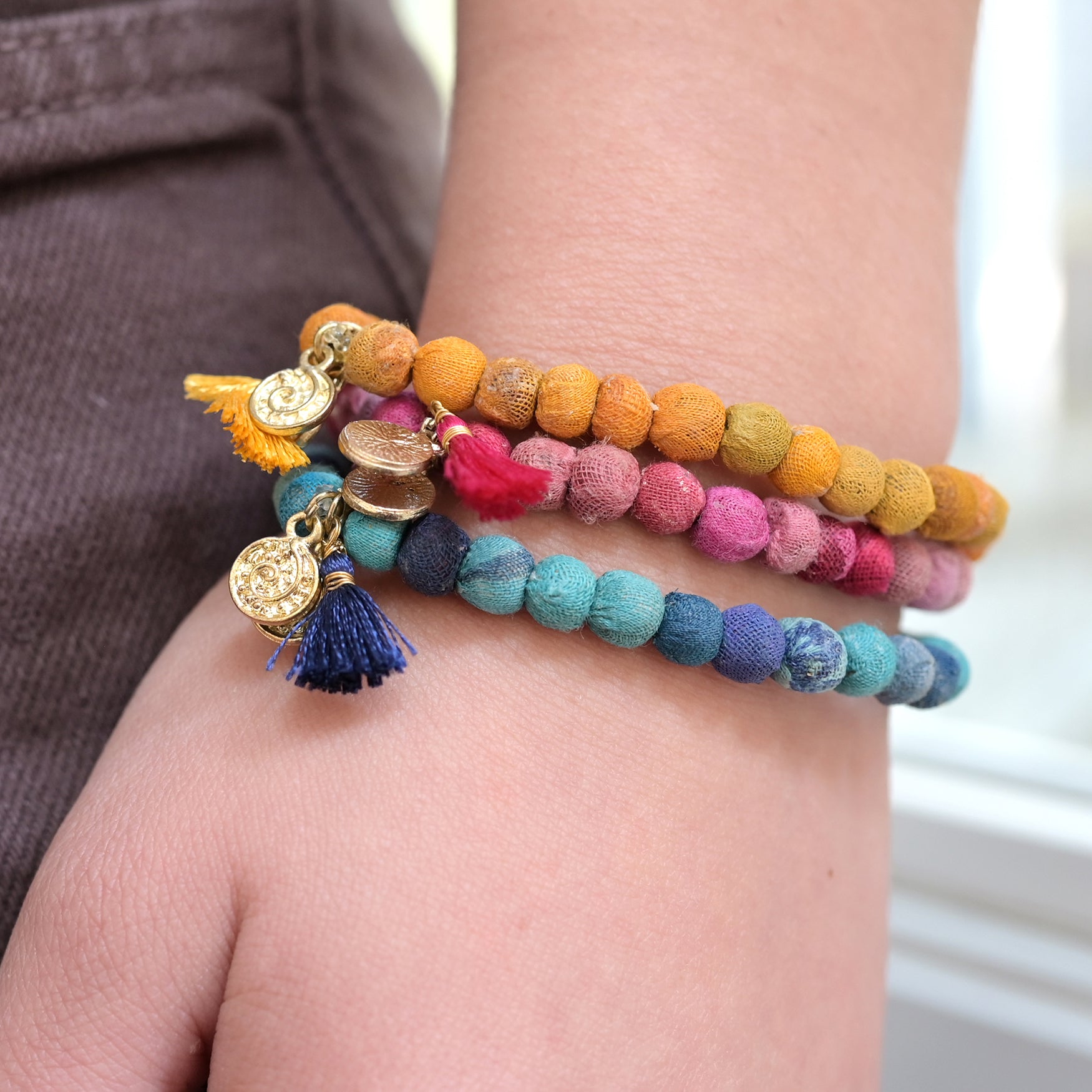 A blue, yellow and pink bracelets adorn a wrist.