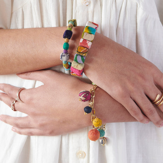 A wrist is adorned with the Kantha Block Bracelet along with other Kantha jewelry styles.