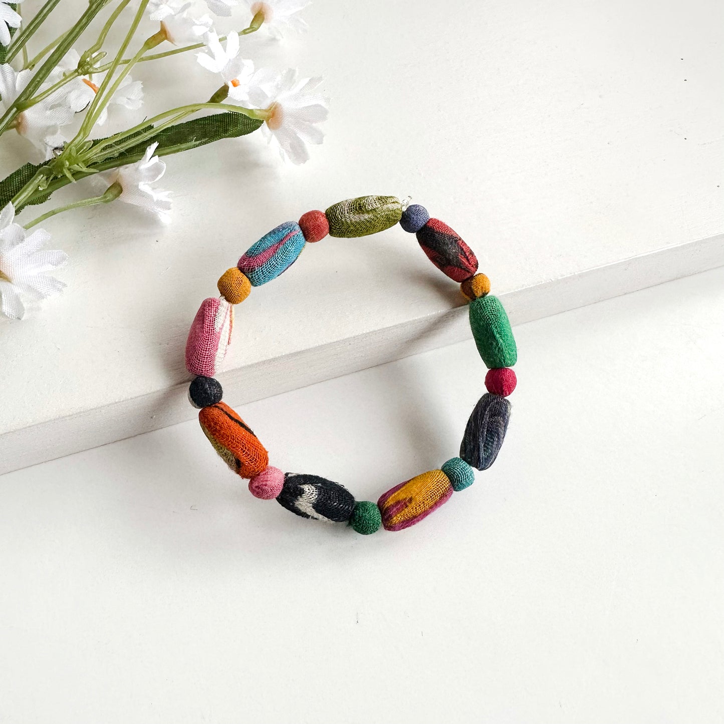 A single-strand bracelet is shown, formed with alternating round and elongated Kantha beads.