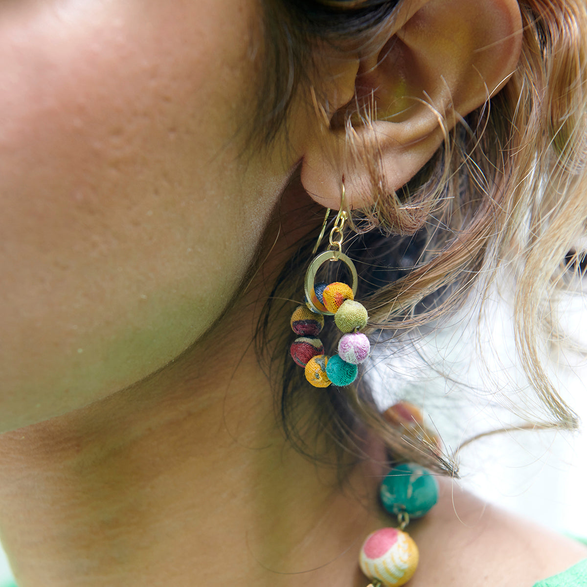 A Kantha Orbital Earring adorns an ear.