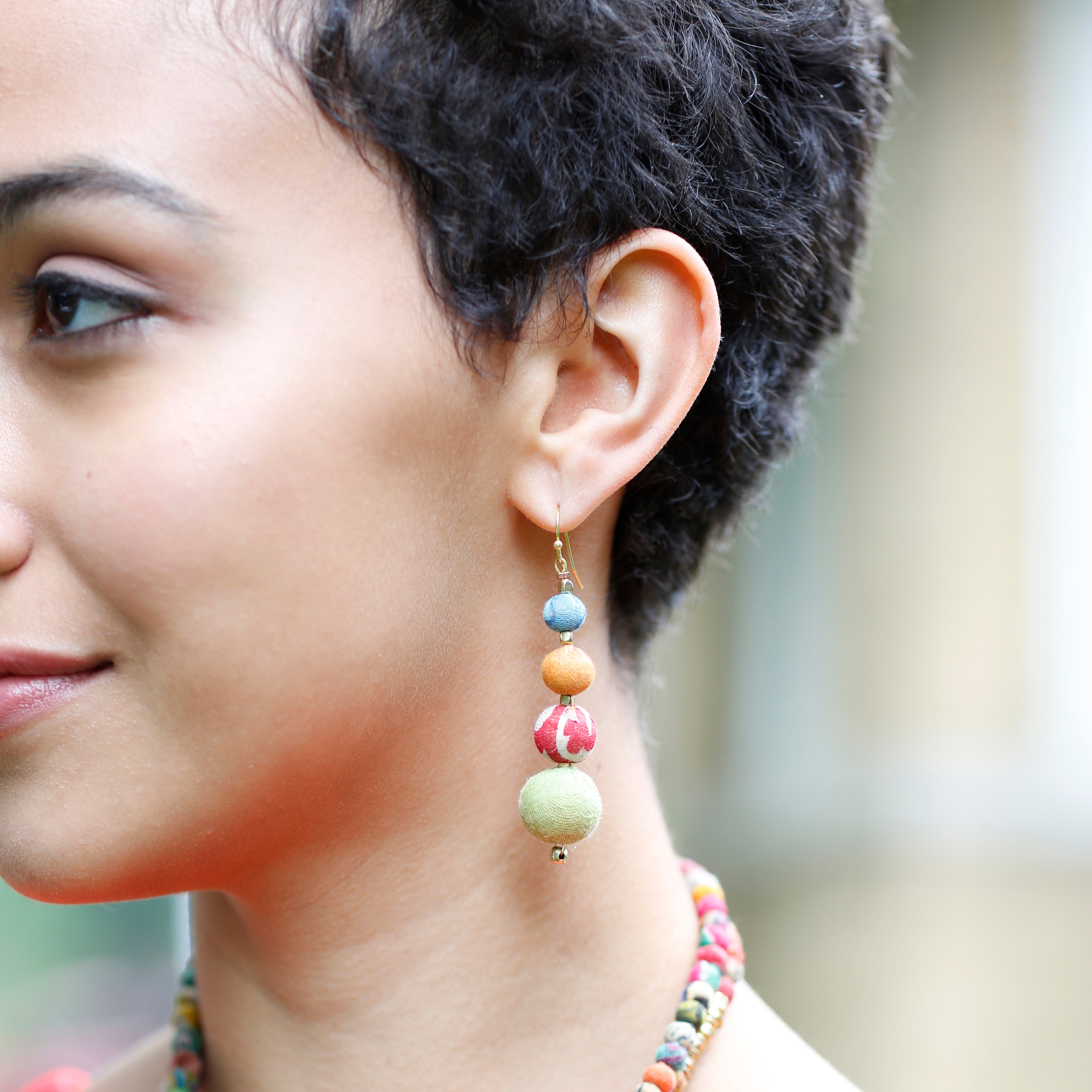 A woman wears the Graduated Kantha Earrings.