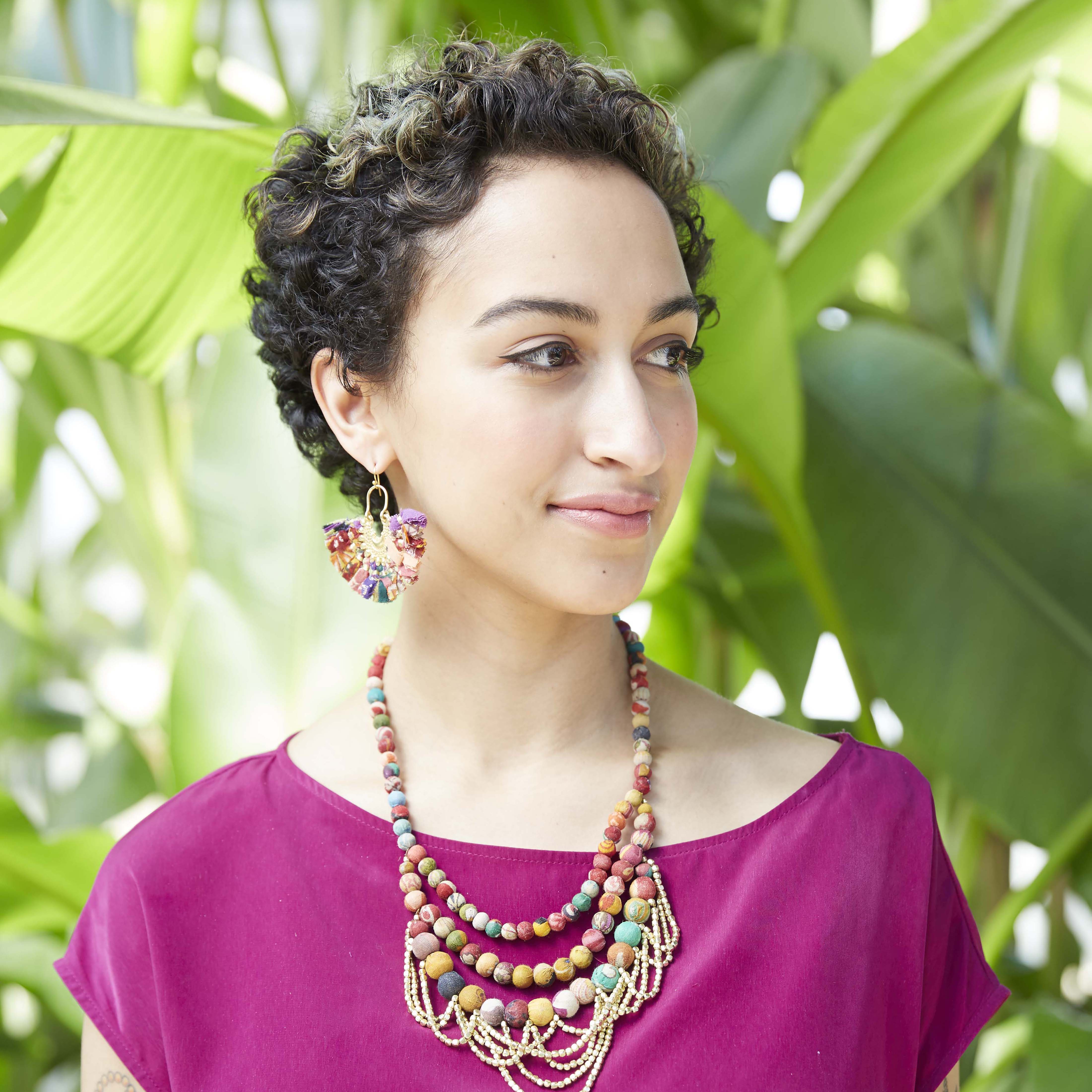 A woman wears the Kantha Ornamental Chandeliers.