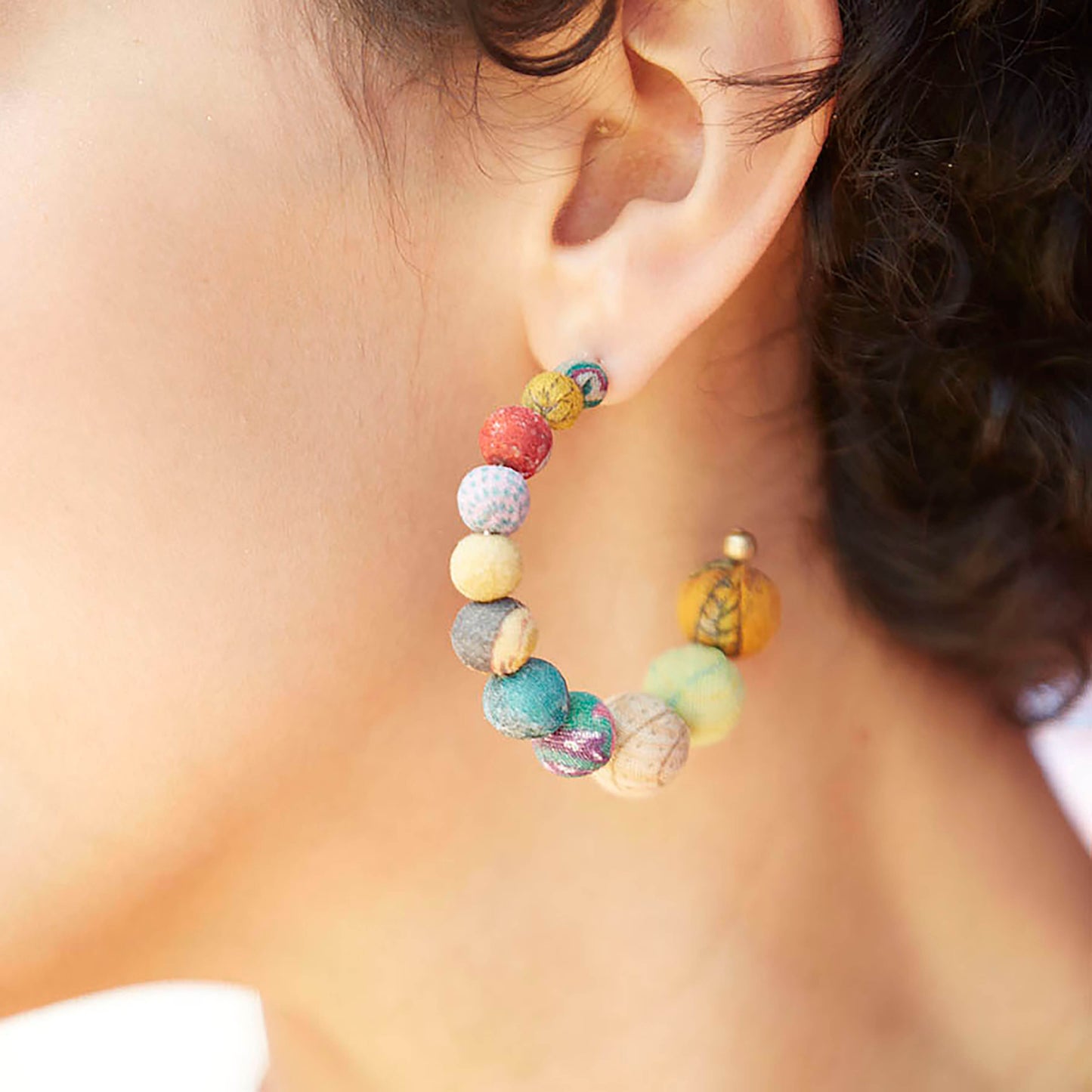 A single Kantha Conch Hoops adorns a woman's ear.