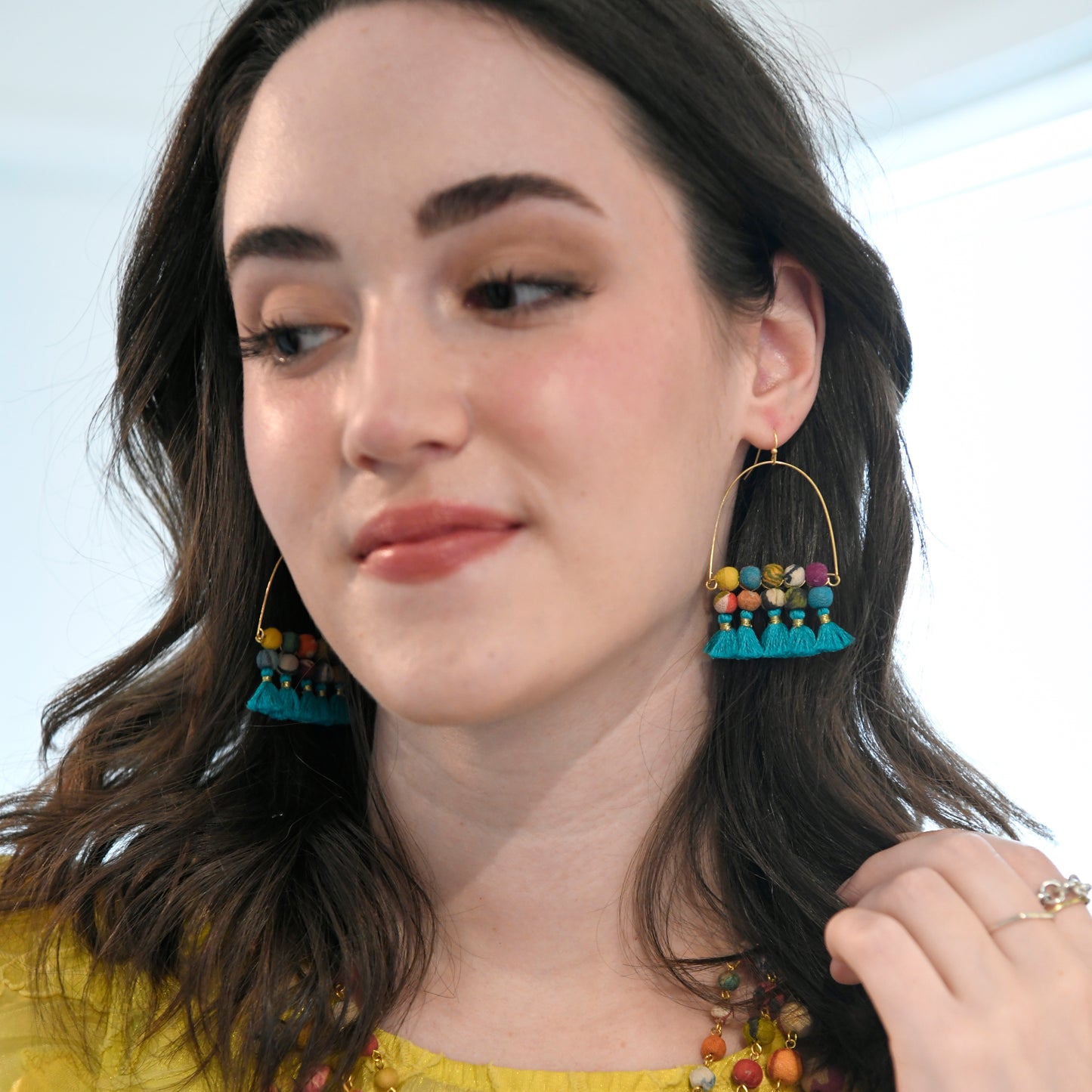 Woman models the blue-fringed Arched Turquoise Tassel Earrings