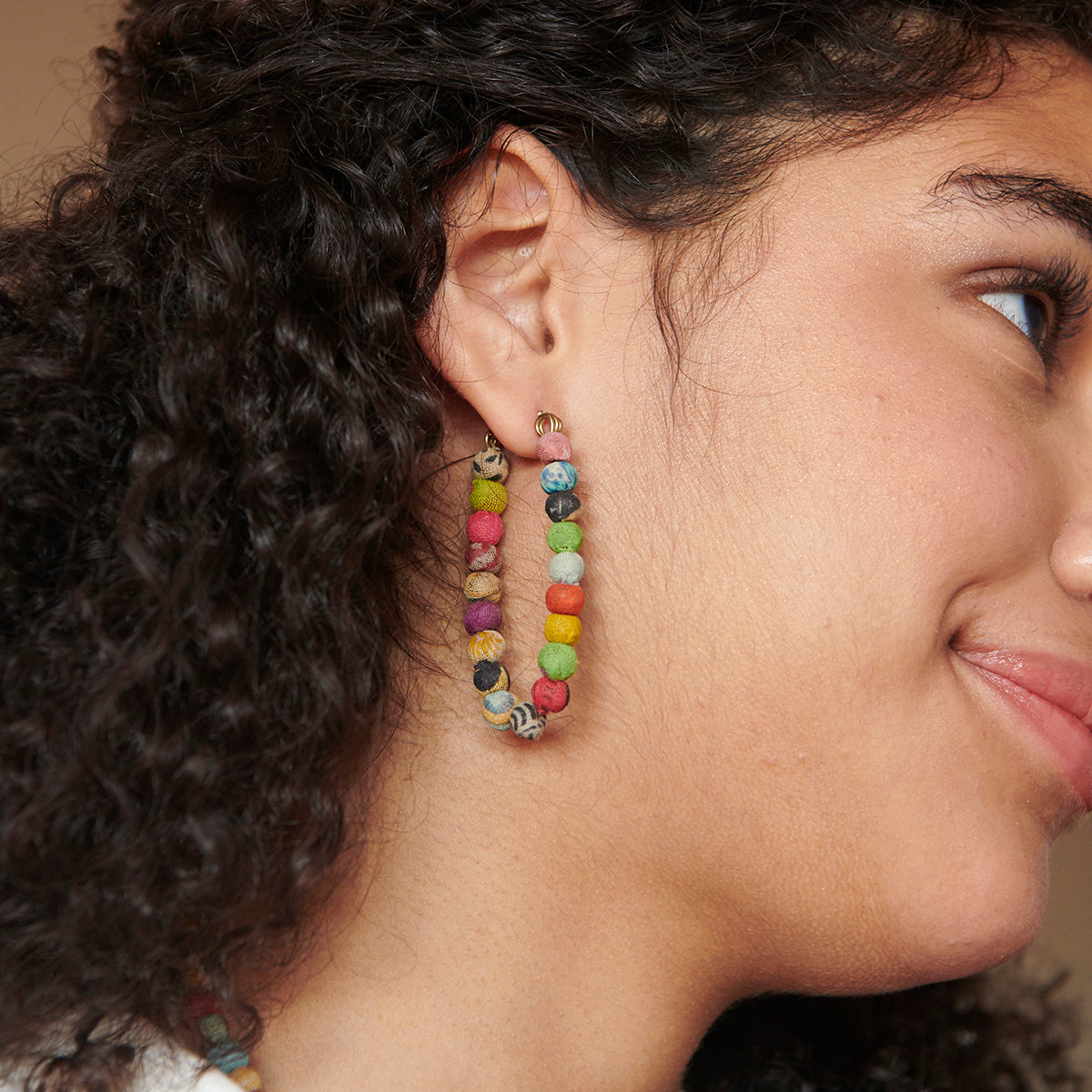 A Kantha Elliptical Hoop adorns a woman's ear.