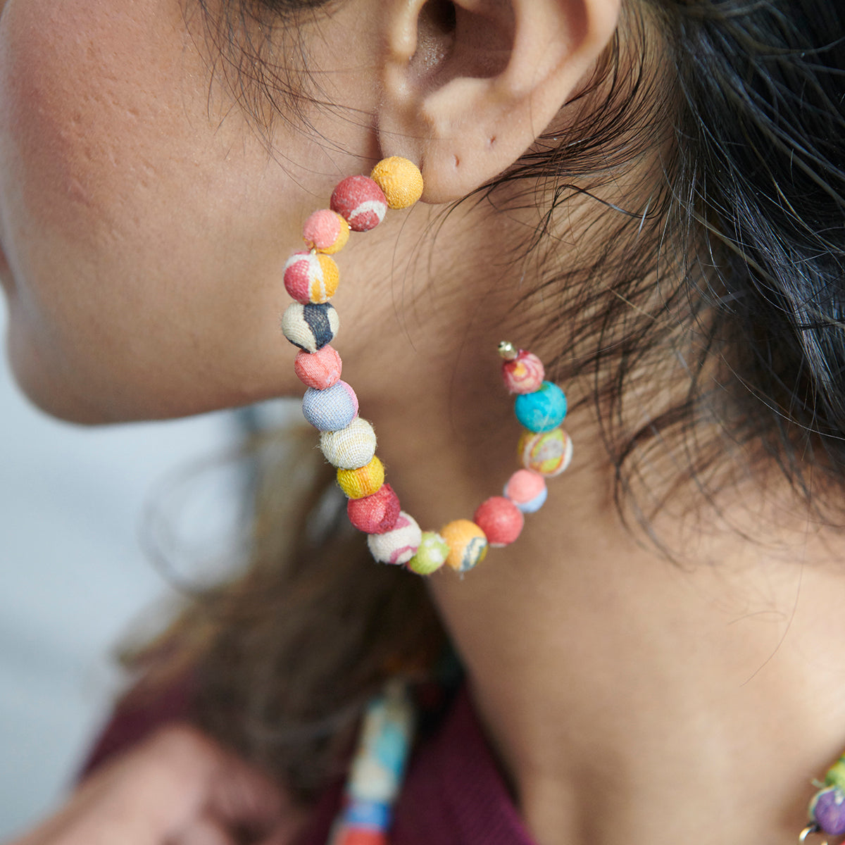 A Kantha Rectangular Hoop adorns an ear.