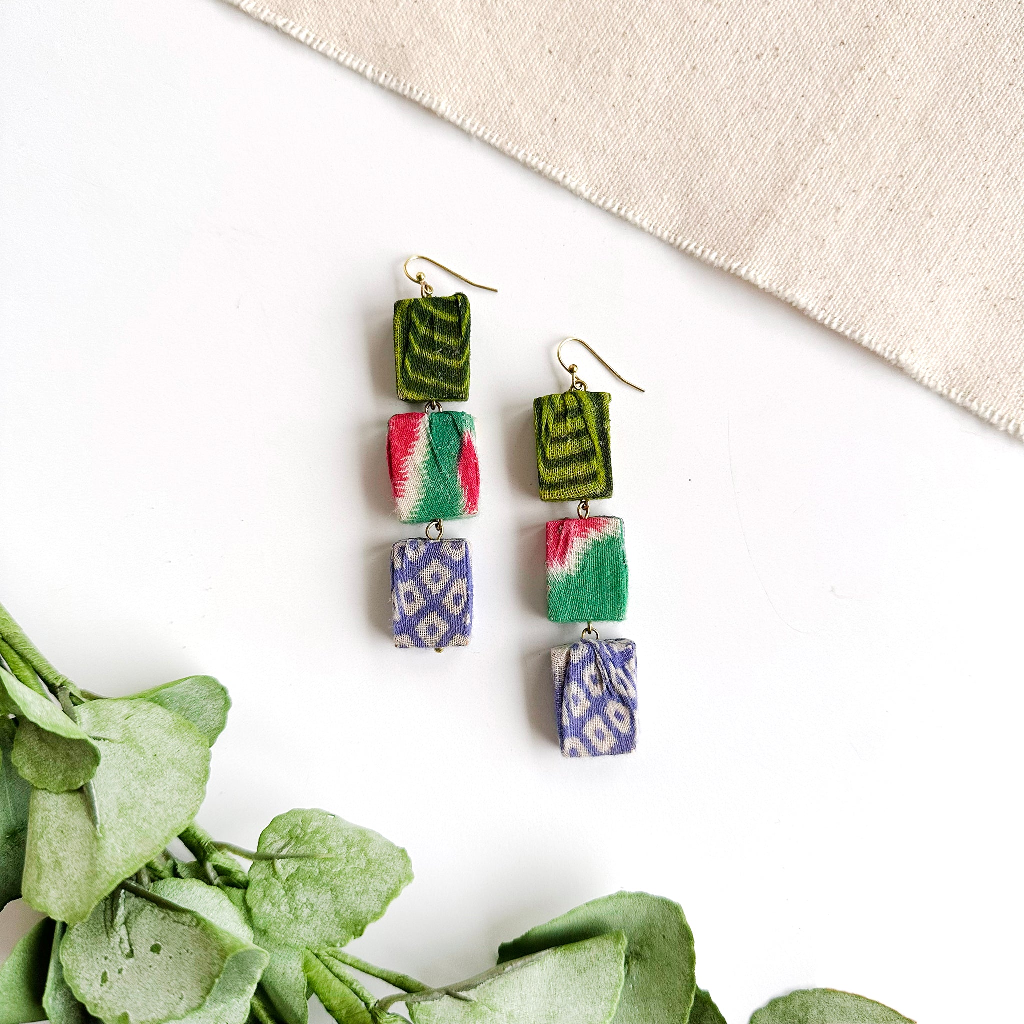 A pair of earrings is shown. These earrings are formed with three rectangular beads hanging vertically from ear wires.