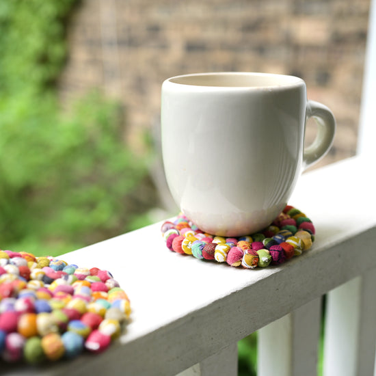 A white mug sits on top of a multicolored Sari Home Circle Coaster