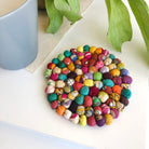 A circular Fabric Bead Sari Home Coaster sits on a table