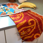 A red Sari Home Tea Towel hangs off a countertop.