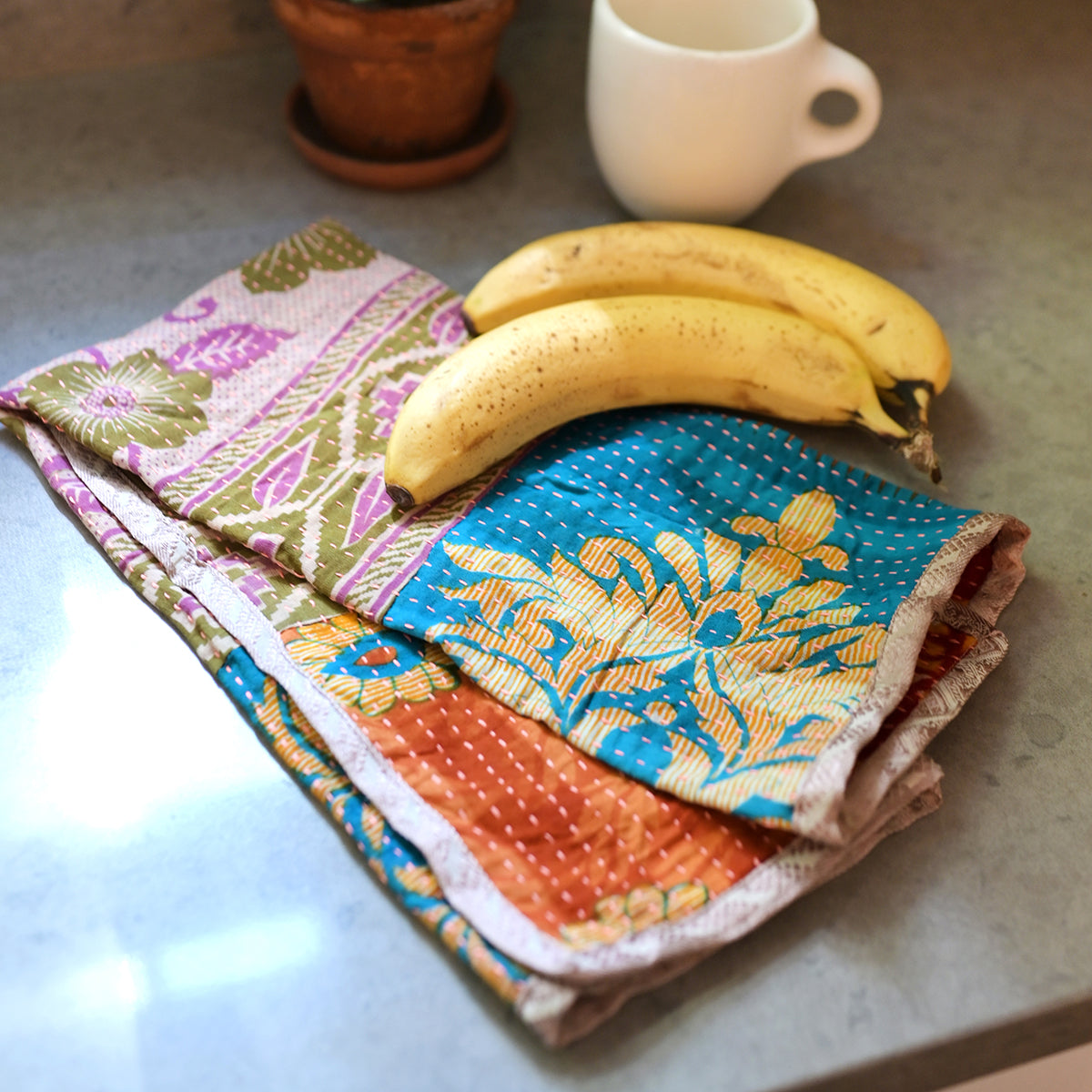 A banana rests on a Sari Home Tea Towel.