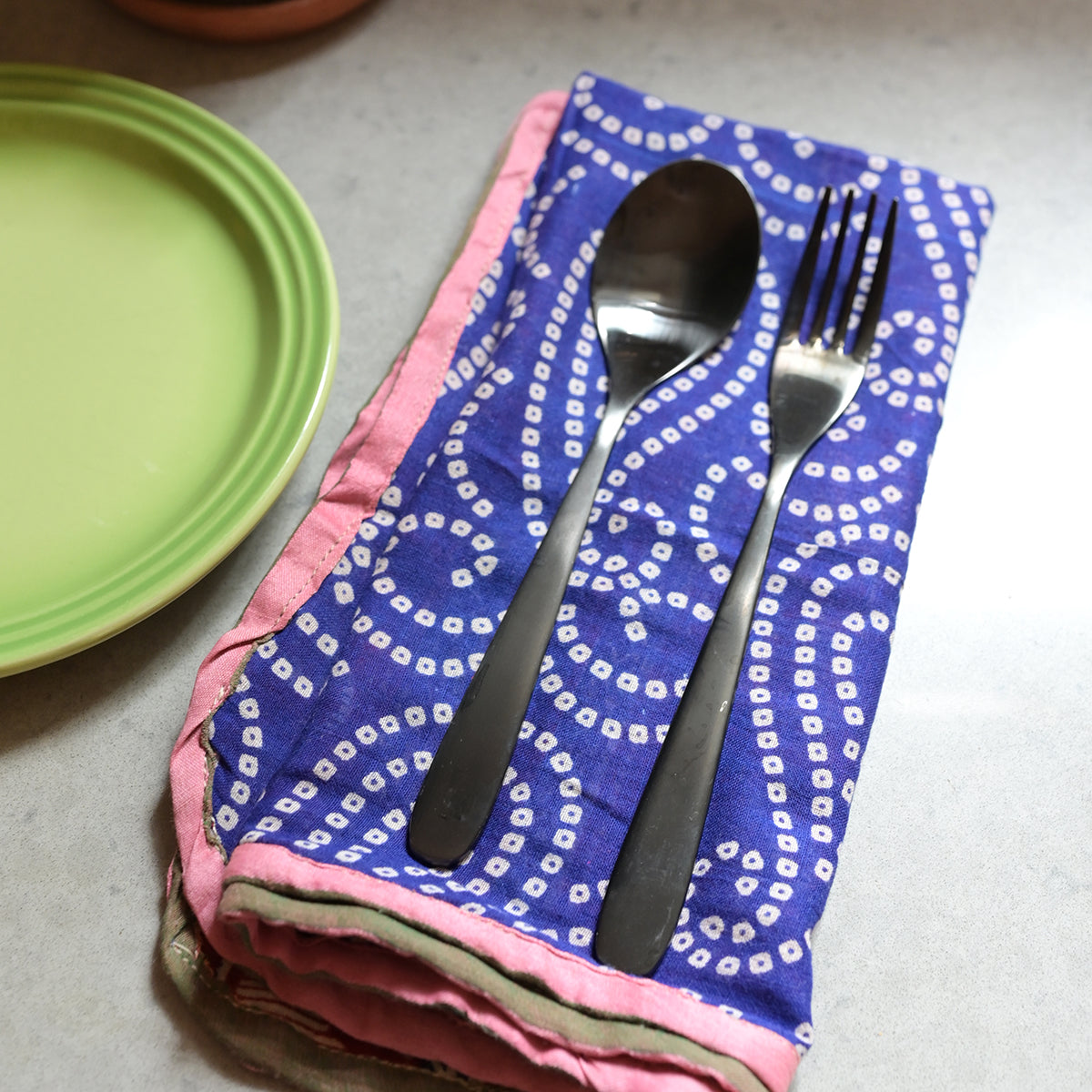 A fork & spoon rest on a blue Sari Home Napkin.