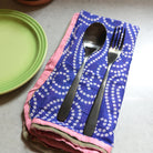 A fork & spoon rest on a blue Sari Home Napkin.