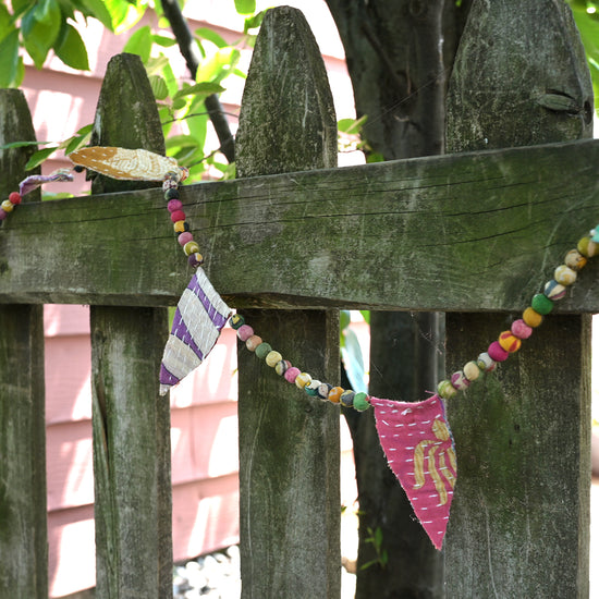 Load image into Gallery viewer, Kantha Bunting Garland hangs on a fence.
