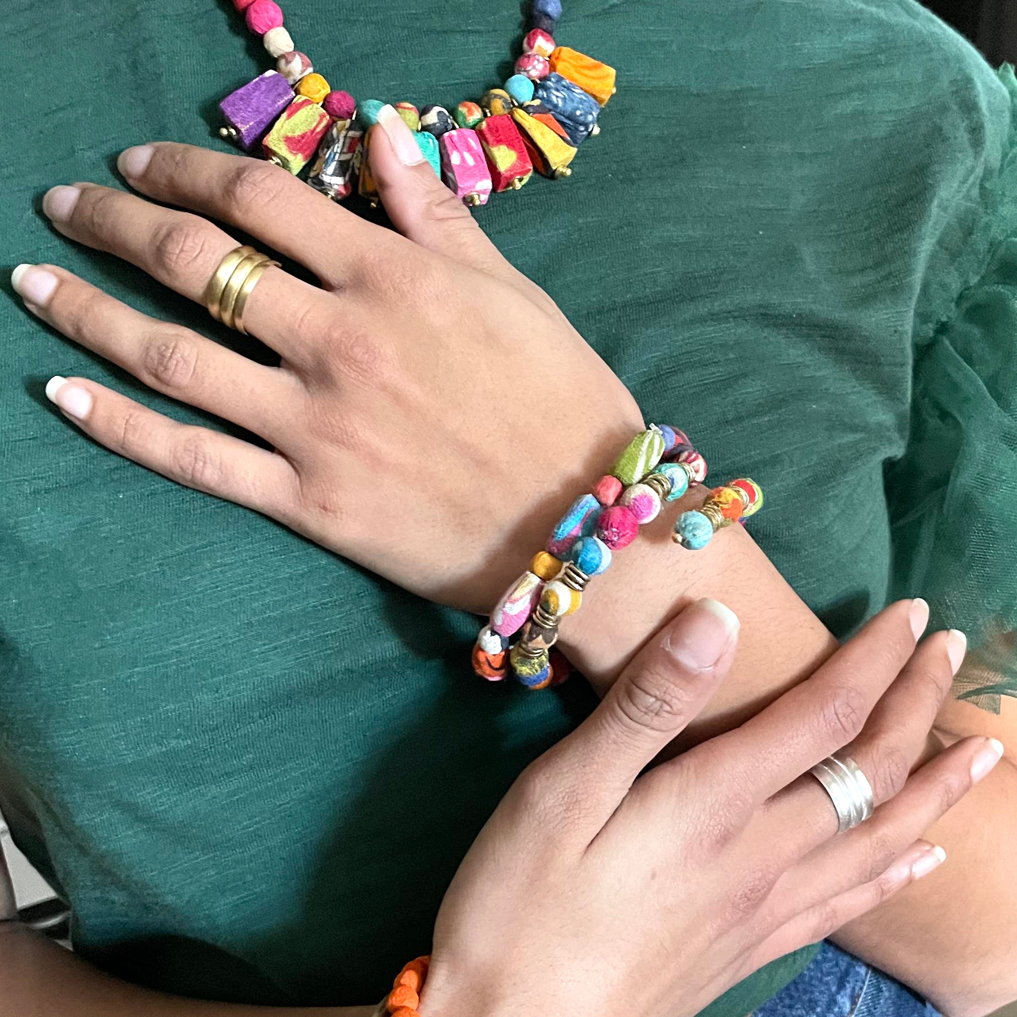 A woman's hand is placed upon her chest, showcasing two bracelets.