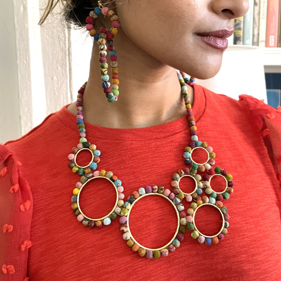 A woman models a colorful beaded necklace.