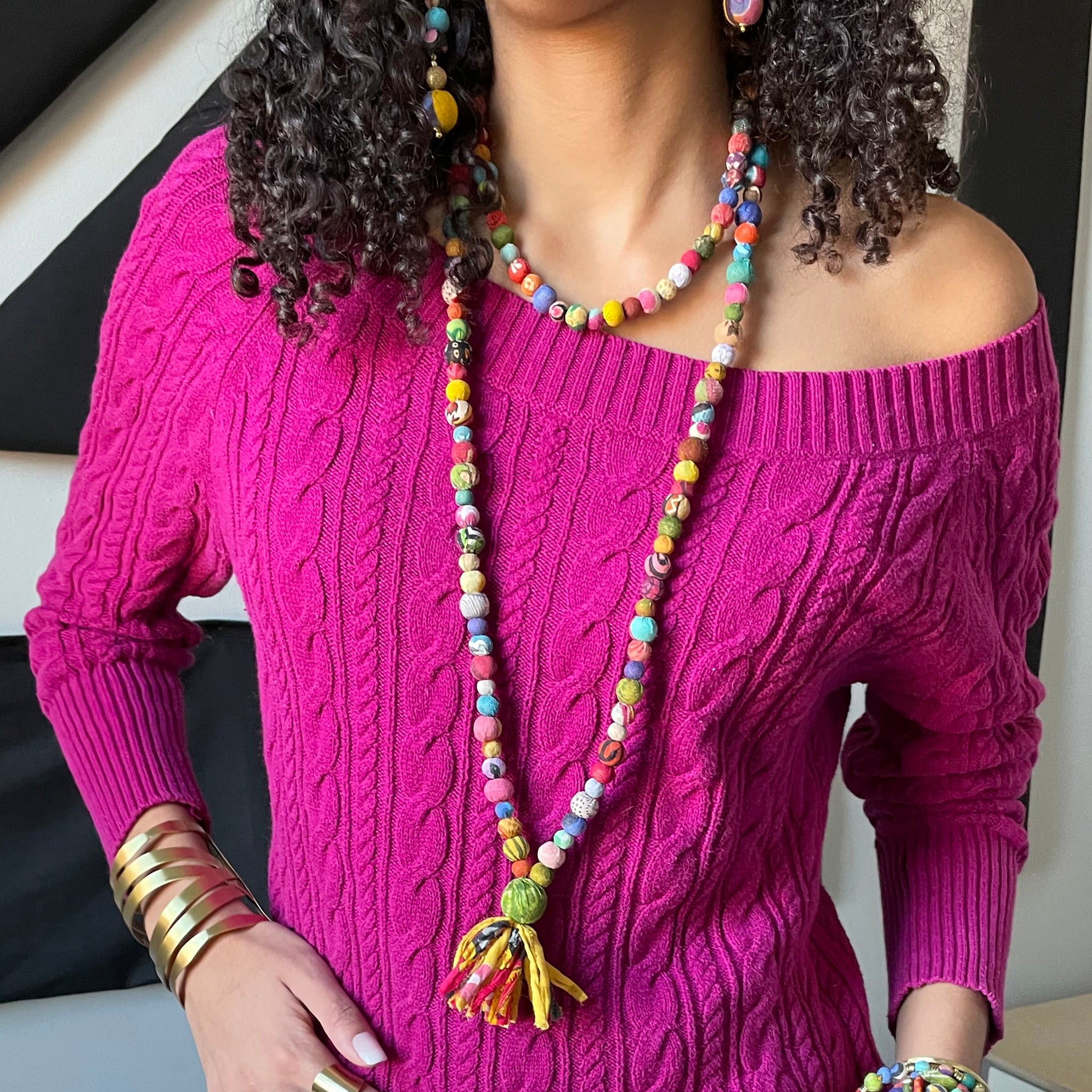 A close up of a woman modeling a colorful two-stranded necklace.