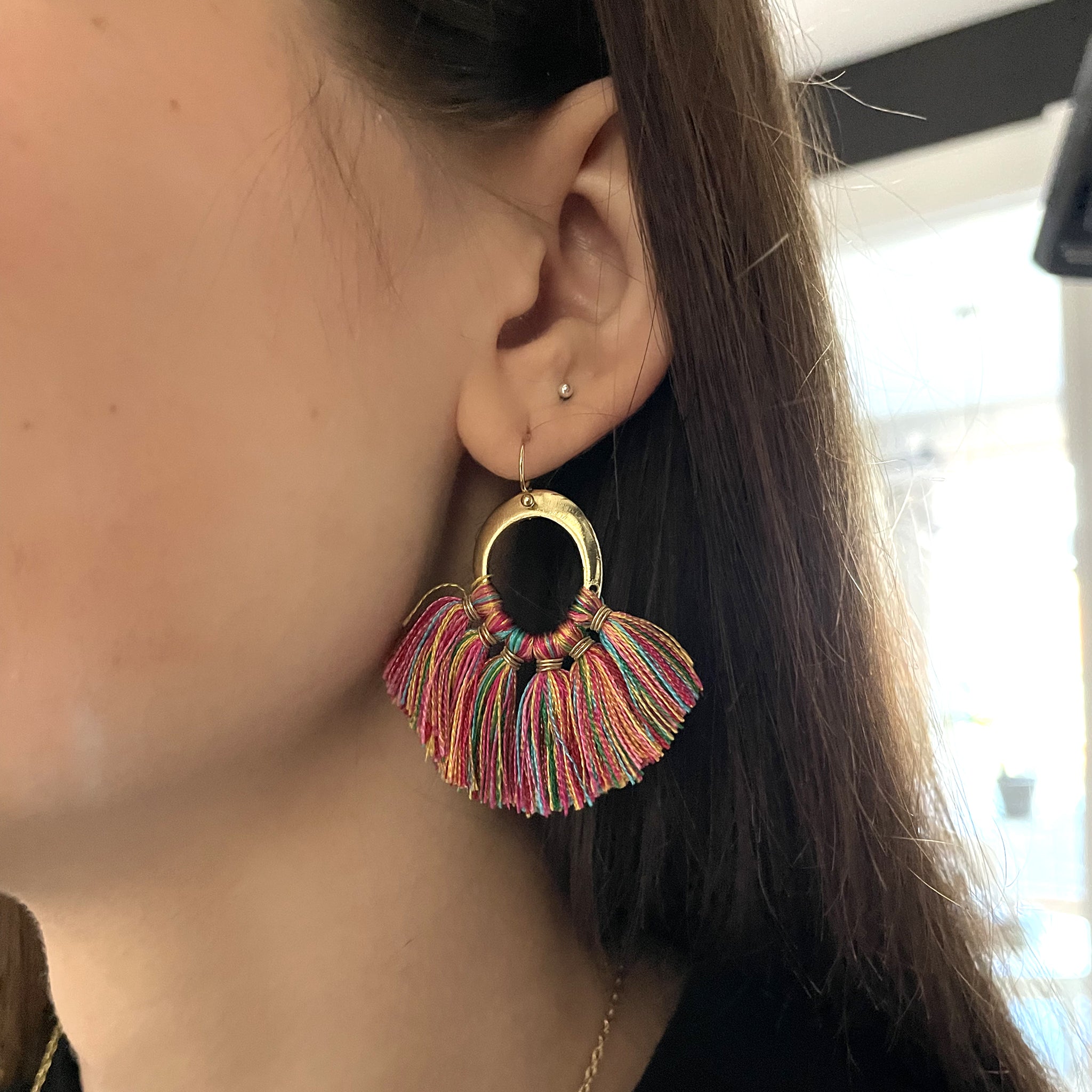 A close-up of an ear showing the Raja Fanned Tassel Earrings.