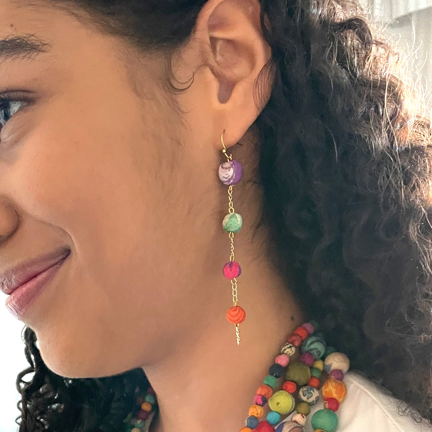 A woman's ear is shown modeling the Kantha Fluid Ellipses Earrings.