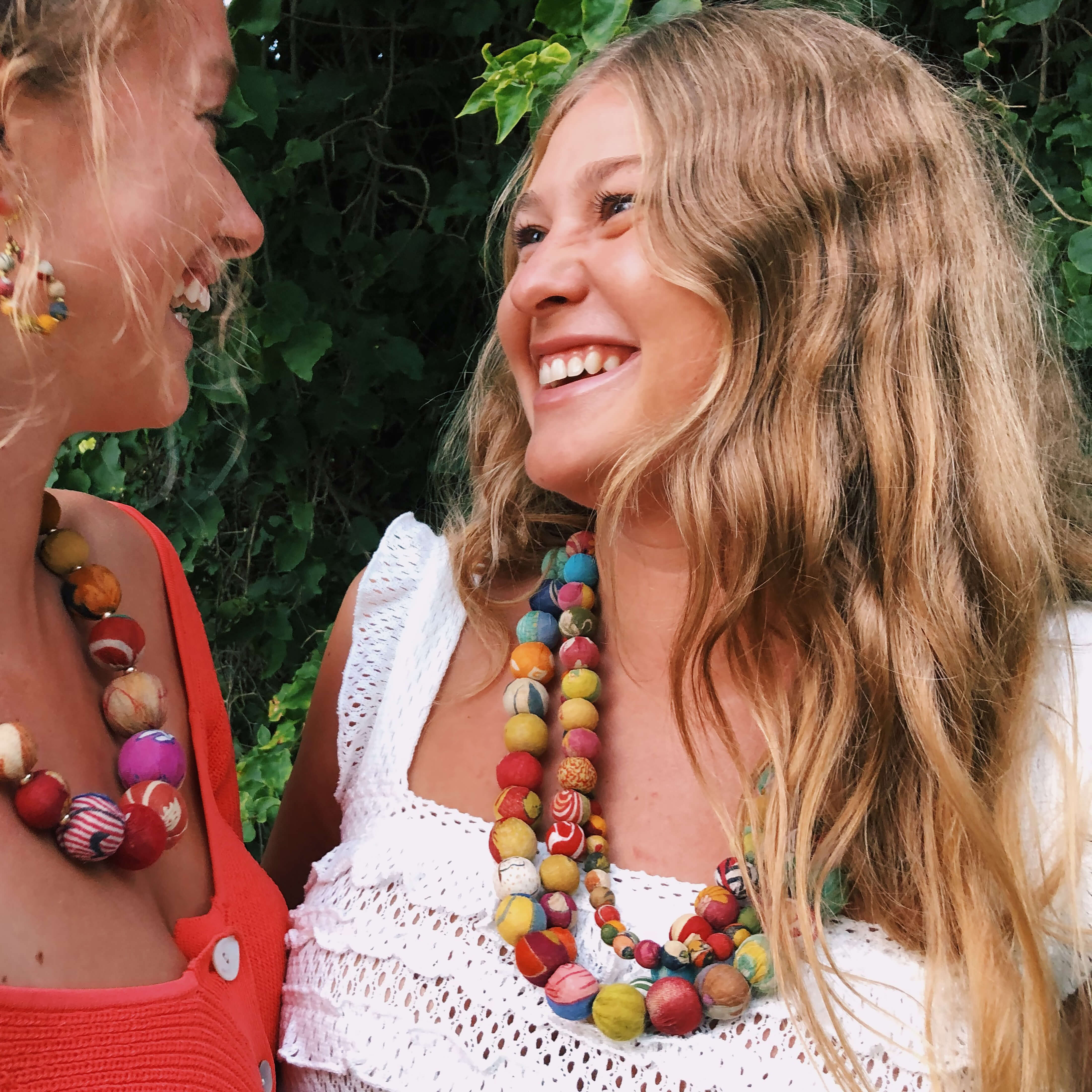 A girl looks at her friends and laughs while wearing the Kantha Calypso Necklace.