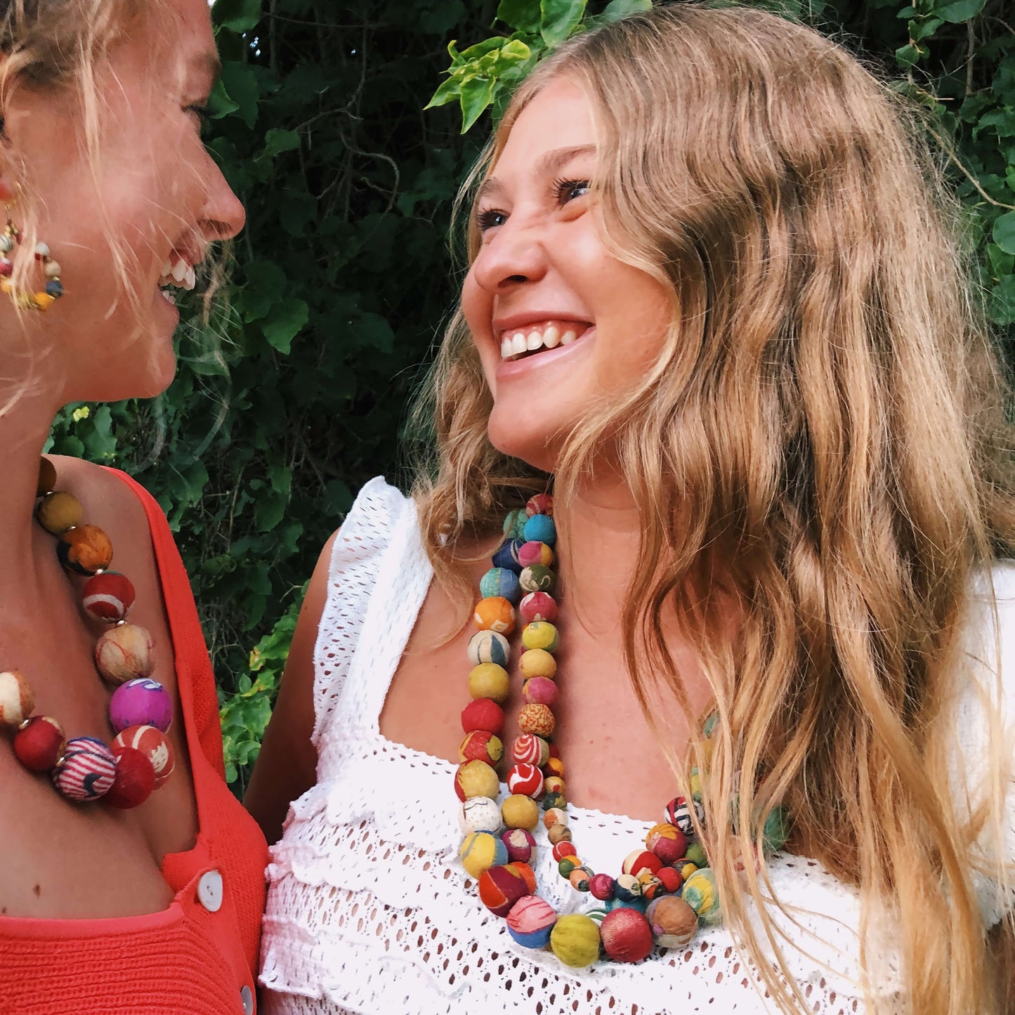 A girl looks at her friends and laughs while wearing the Kantha Calypso Necklace.