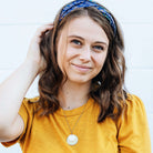 A model wears the Eclipse Necklace and a blue neckerchief in her hair.