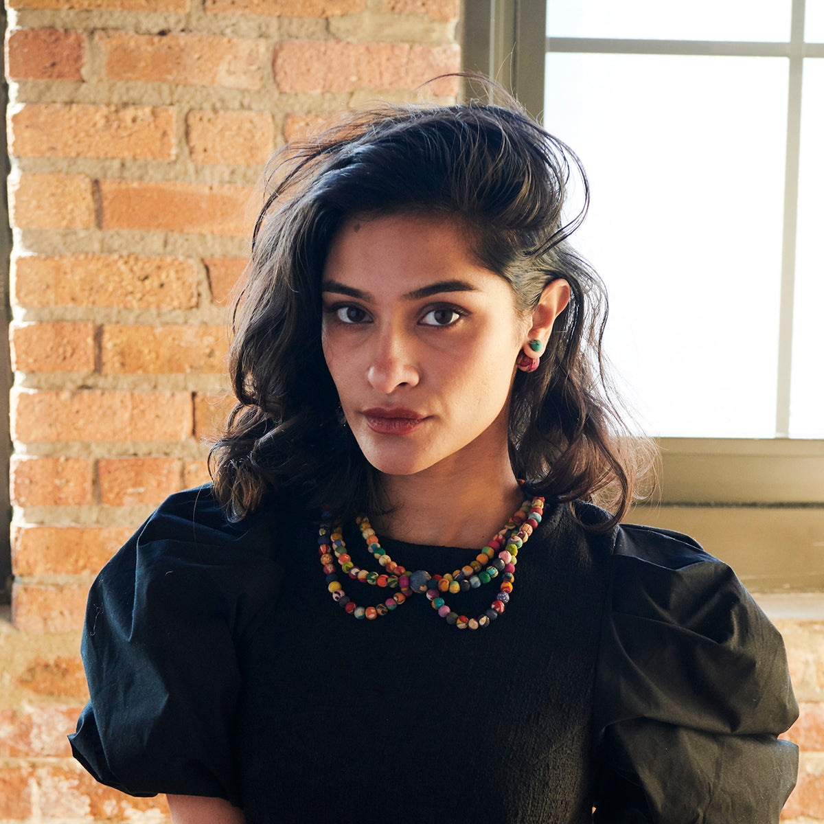 A model wearing black wears the Kantha Portrait Necklace.
