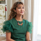 A woman smiles while modeling colorful beaded jewelry.