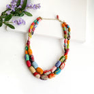 A two-strand necklace is formed with oblong textile-wrapped beads.