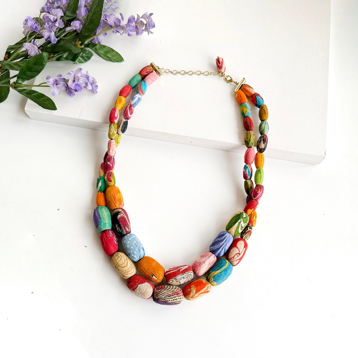 Load image into Gallery viewer, A two-strand necklace is formed with oblong textile-wrapped beads.
