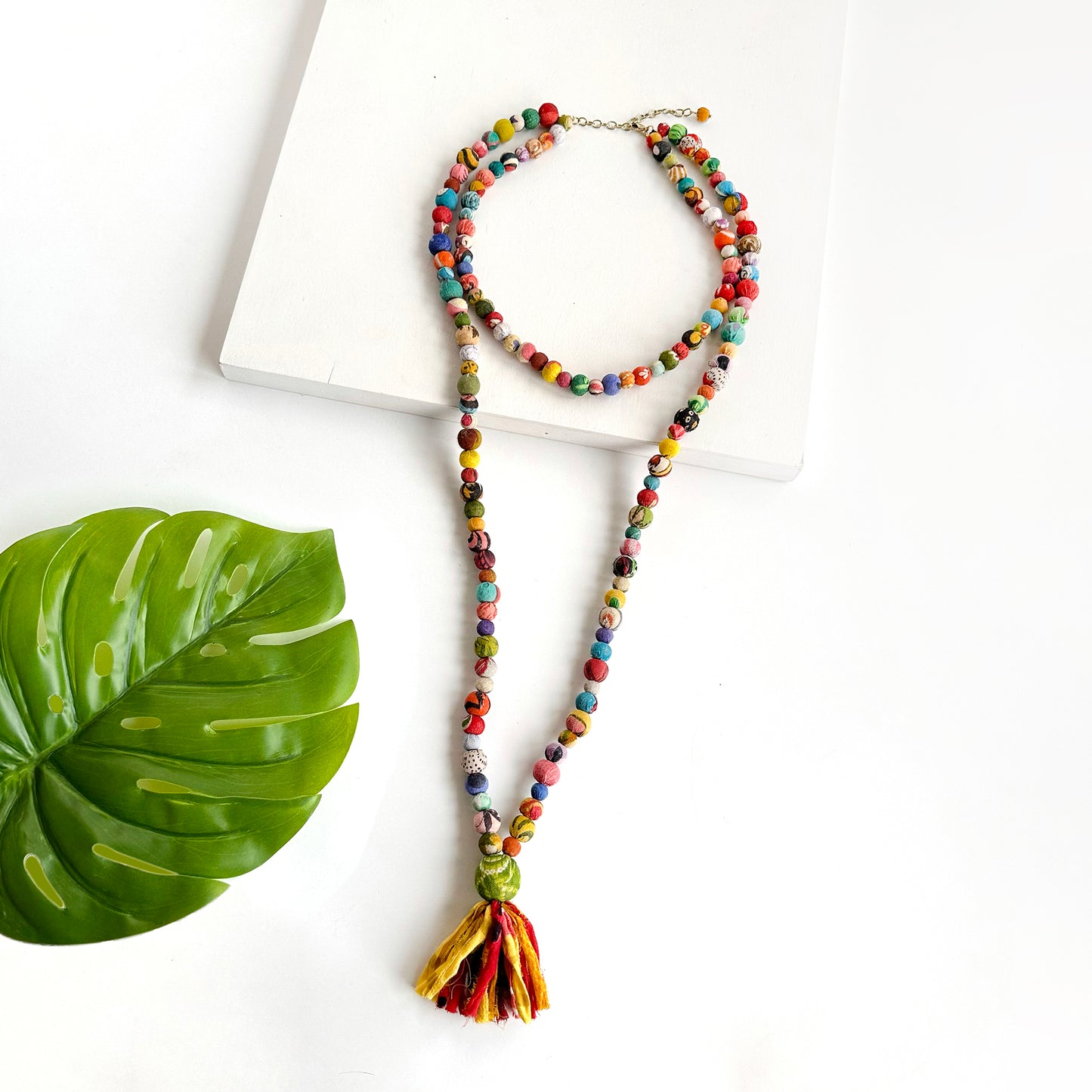 Load image into Gallery viewer, Two connected strands of colorful textile wrapped beads is punctuated with a tassel.
