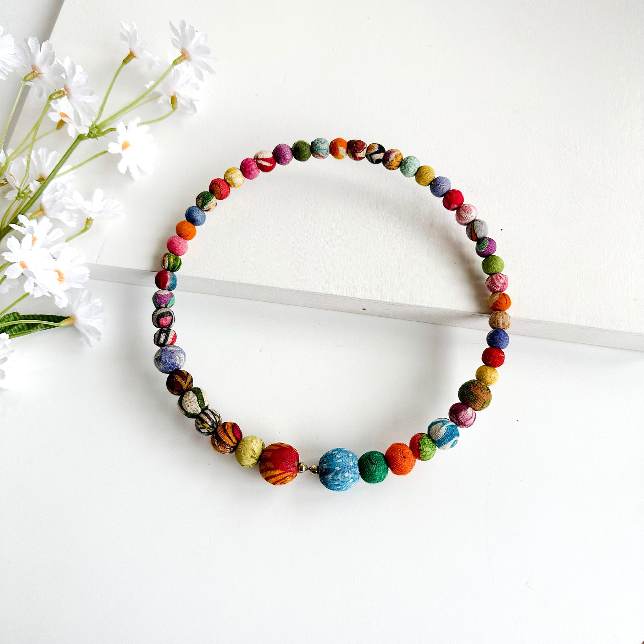 A circle of colorful textile-wrapped beads on a memory wire form this classic choker silhouette.