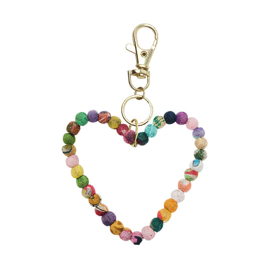 A heart formed from textile-wrapped beads is topped with a metal circle and lobster clasp.