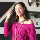 A model smiles at us while wearing colorful beaded jewelry.