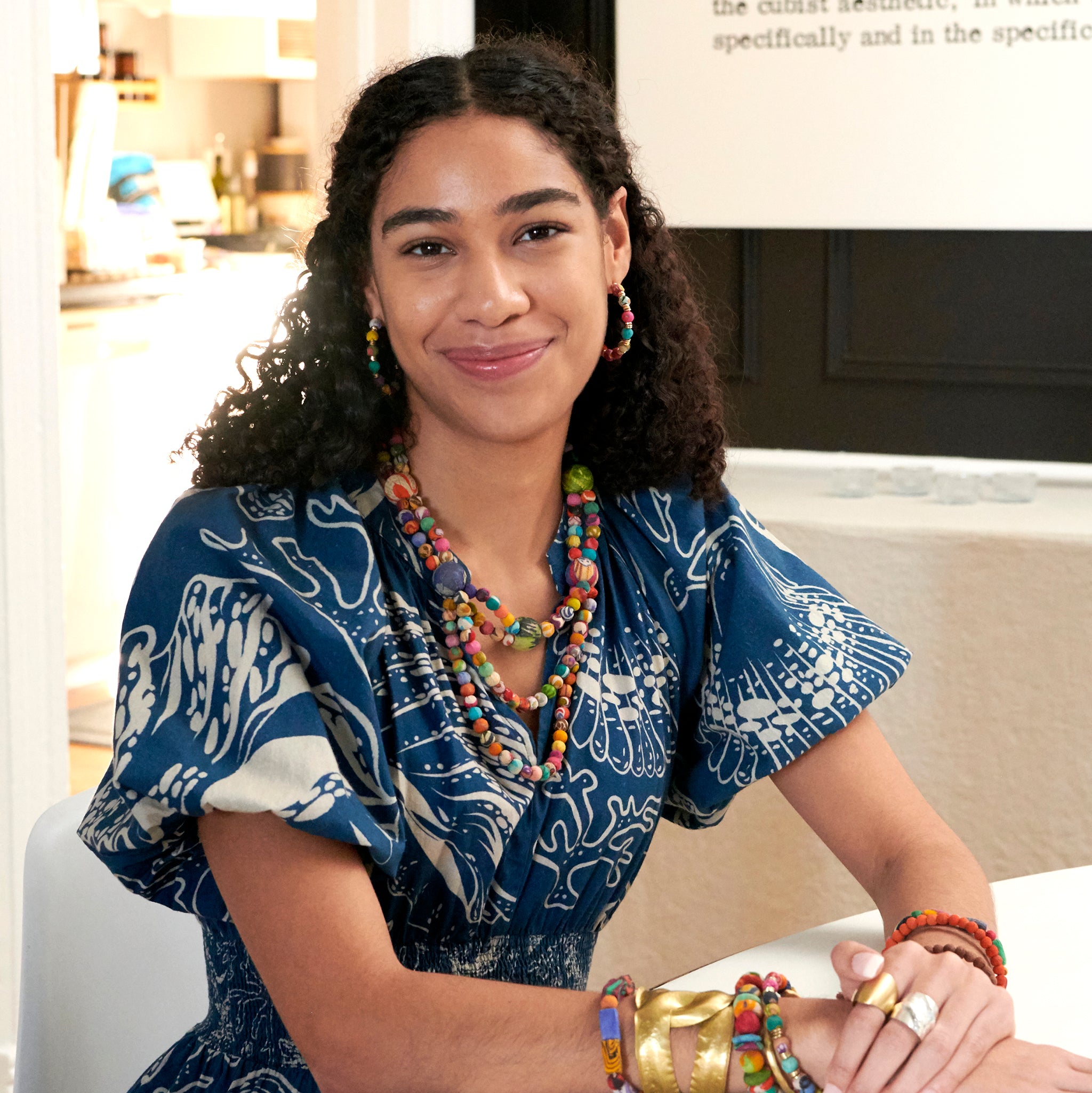 A woman smiles at us while wearing the Kantha Society Necklace.