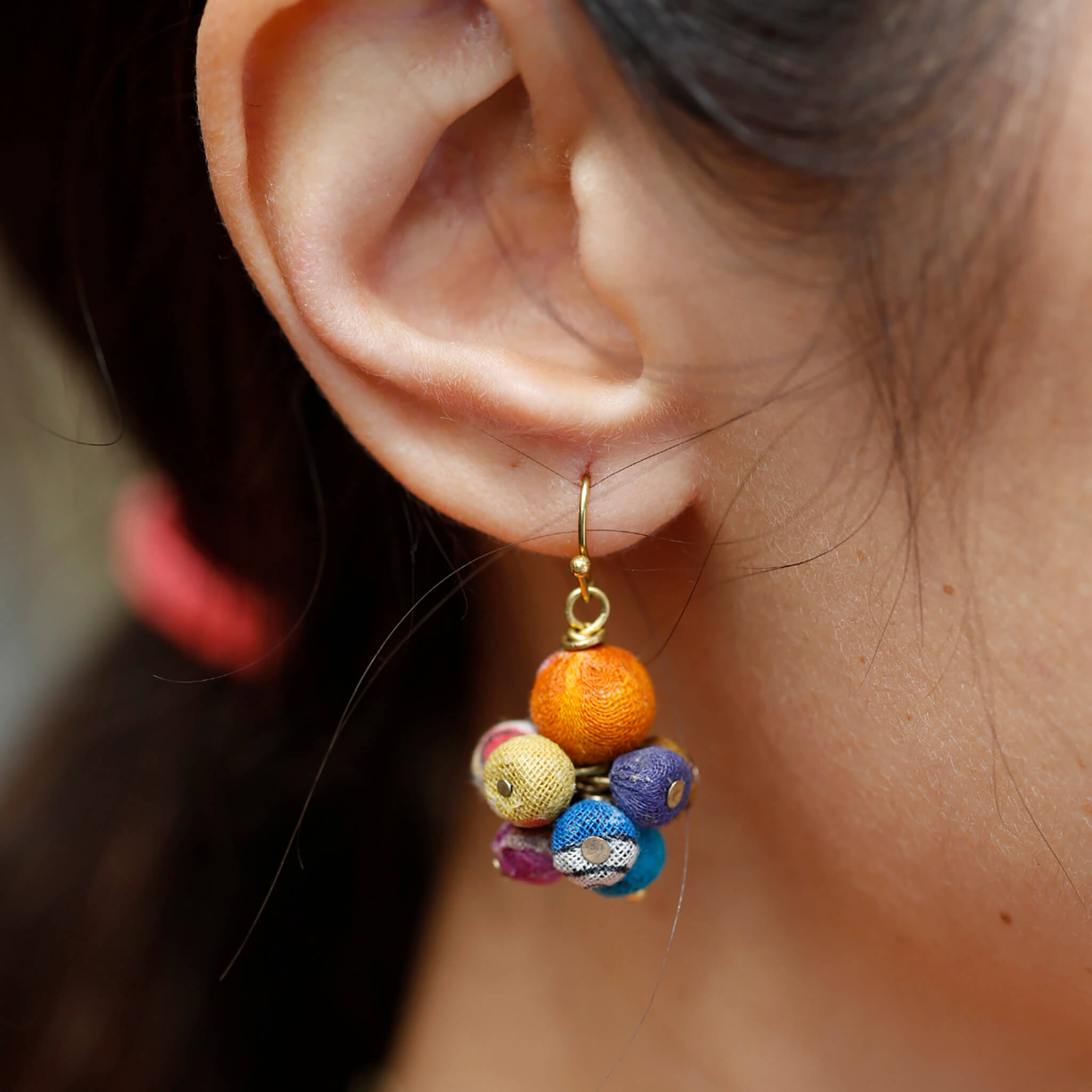 A close-up of a woman's ear and the multicolor, beaded earring she is wearing.