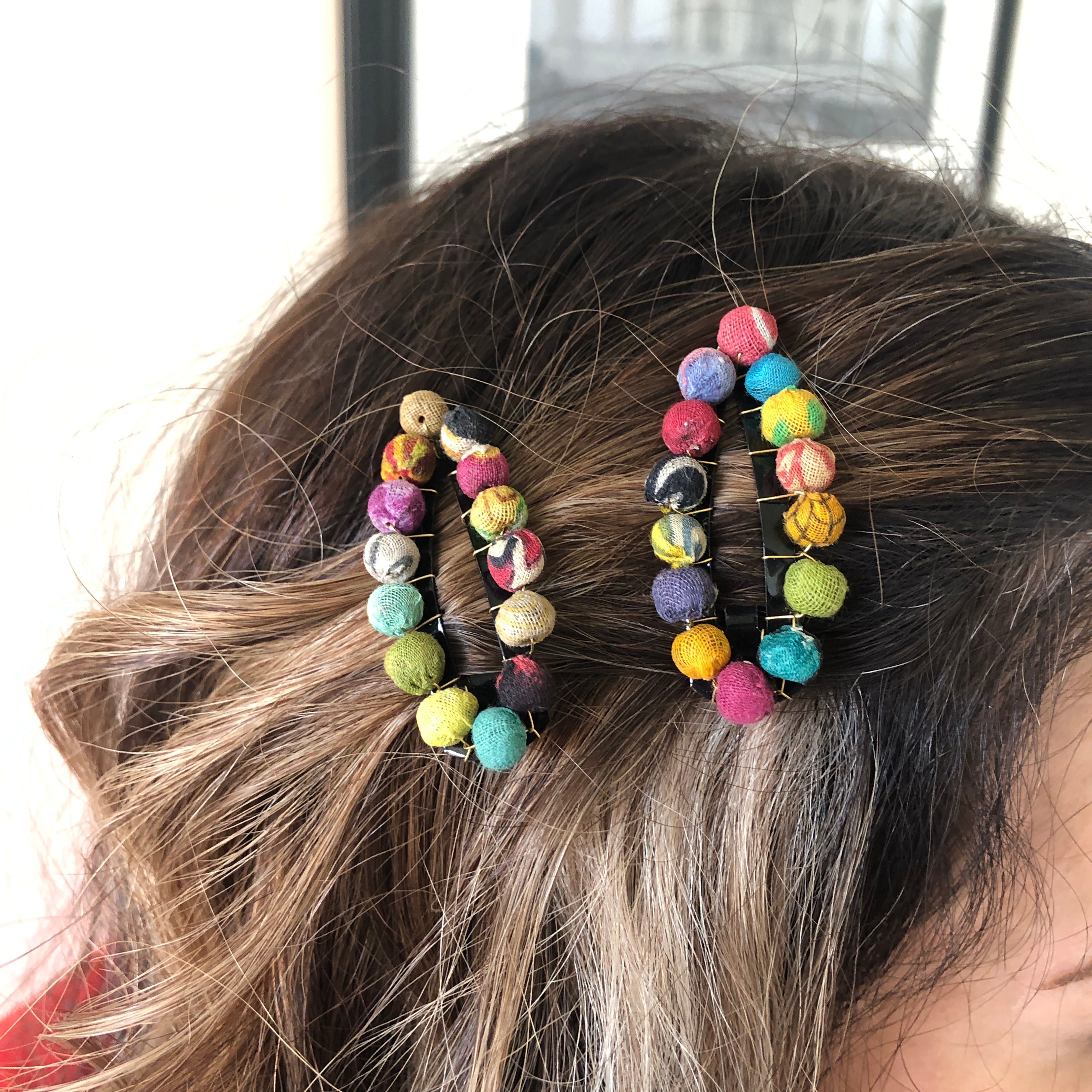A close up of a woman's two multicolor beaded hair clips she is wearing.